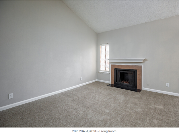 An empty living room with a fireplace and a window.