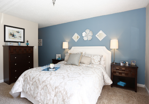 A bedroom with blue walls and a white bed