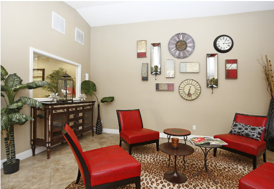 A living room with red chairs and a clock on the wall