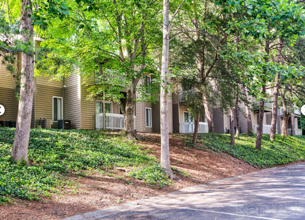 A row of apartment buildings surrounded by trees and bushes.