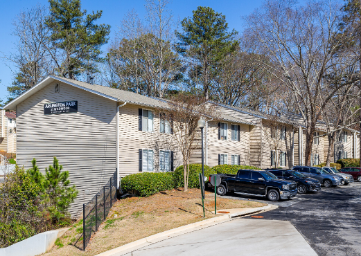 A large apartment building with a lot of cars parked in front of it.