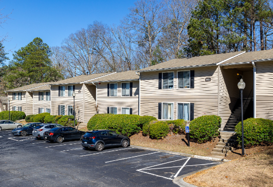 A row of apartment buildings with cars parked in front of them.