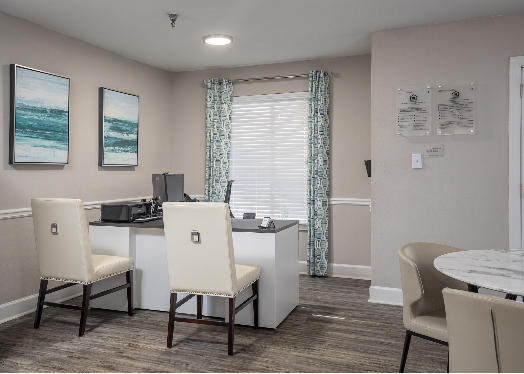 A room with a desk , chairs , a table and a window.