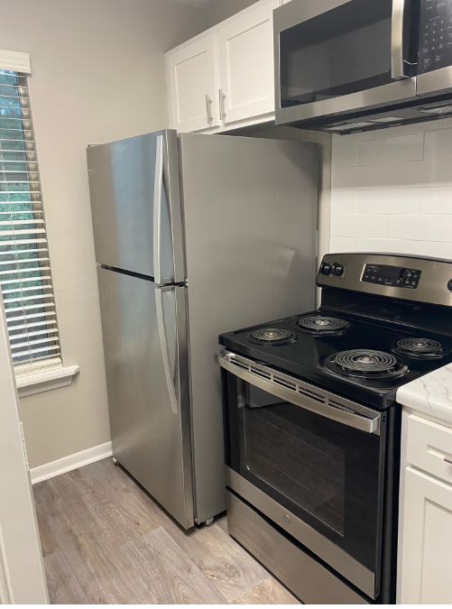 A kitchen with a refrigerator , stove , and microwave.