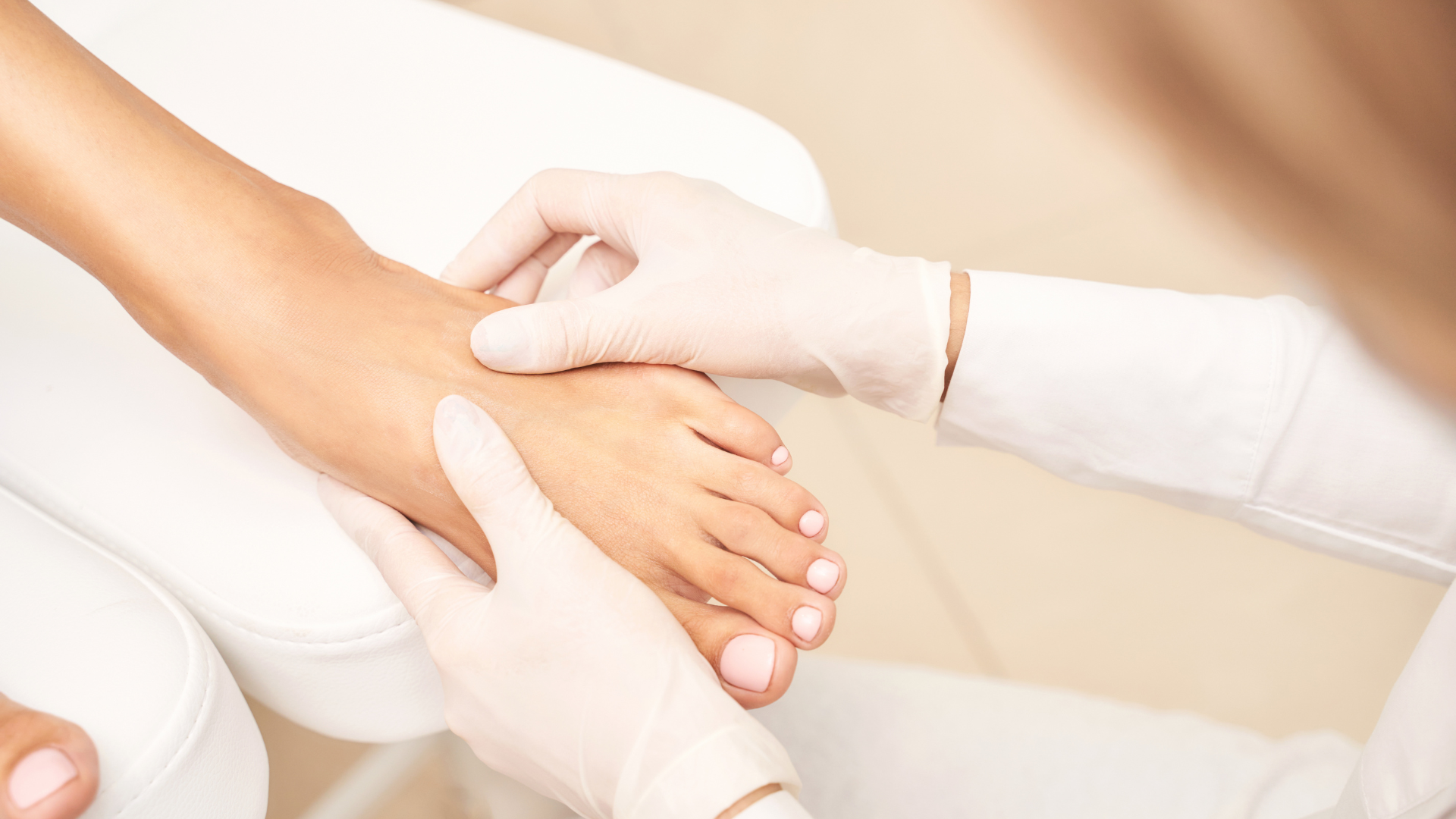 Person's foot being examined by a gloved person, likely during a foot care procedure.