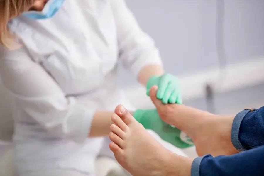 Person's foot being examined by a healthcare professional in a clinic setting.