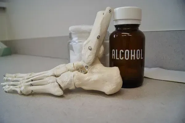 Foot skeleton model next to an alcohol bottle and a jar of cotton.