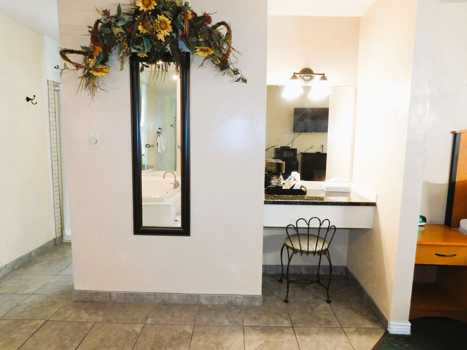 Hotel room interior with a vanity area, long mirror, and floral decor.