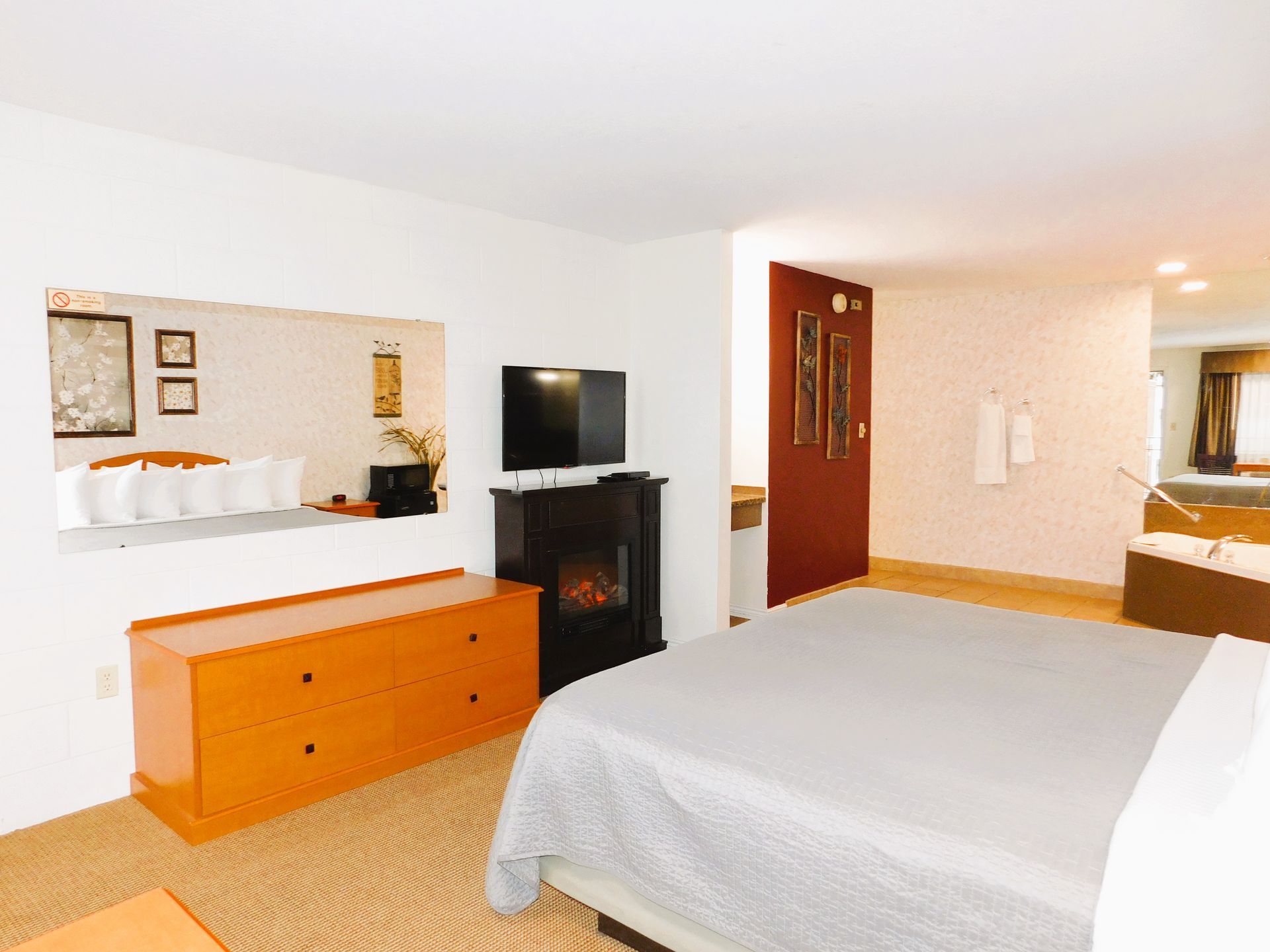 Bedroom with a gray bed, orange dresser, fireplace, mirror, and doorway.