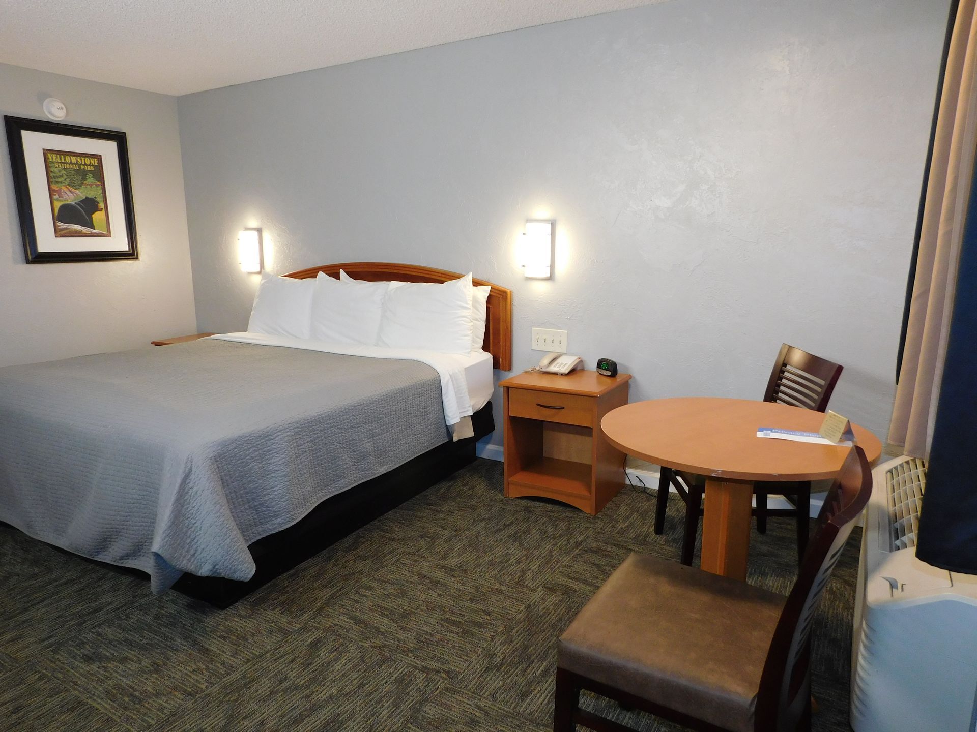 Hotel room with a bed, nightstand, table, and two chairs.
