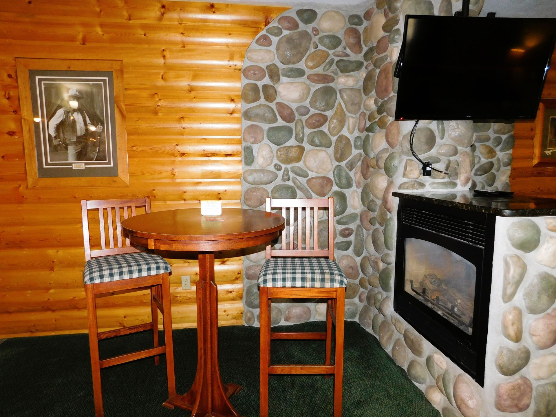 Cozy cabin area with a table, chairs, fireplace, TV, and log walls.