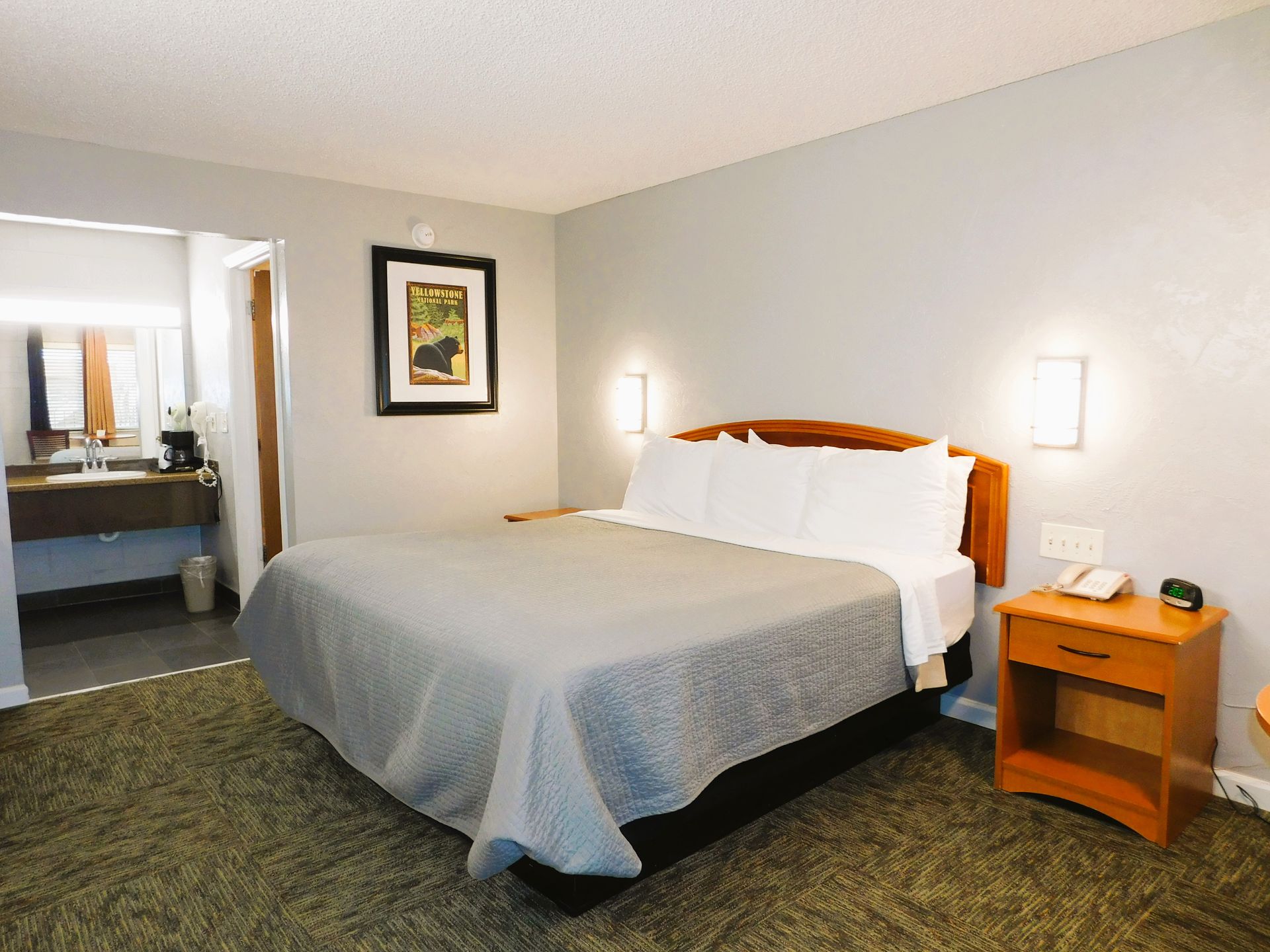 Bedroom with bed, nightstand, framed art, and bathroom doorway.