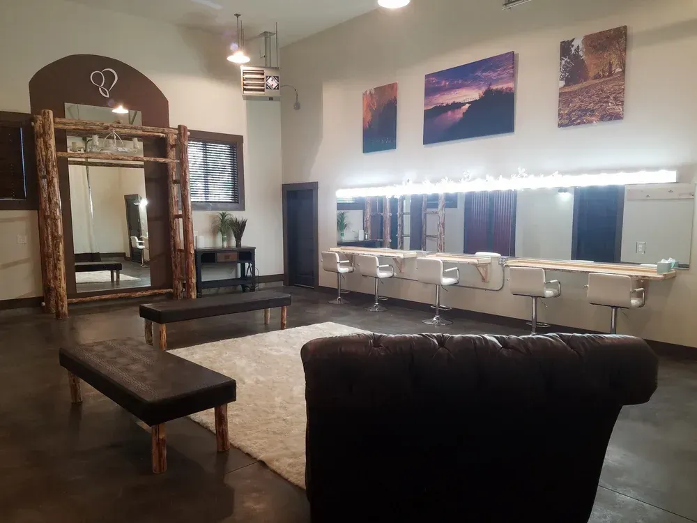 A dressing room with a vanity mirror station, seating benches, a white rug, and wall art in a modern, spacious studio.