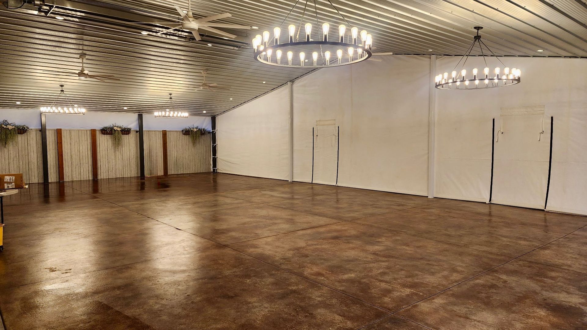 Empty banquet hall with polished floor, white walls, and modern chandeliers overhead
