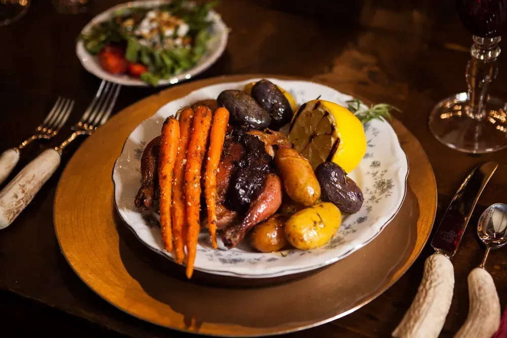 Roast dinner with carrots, potatoes, meat, and gravy on a white plate at a table
