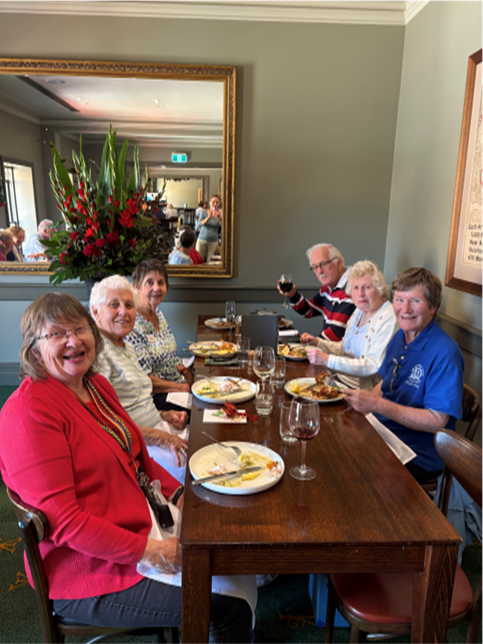 A group of people are sitting at a table with plates of food.