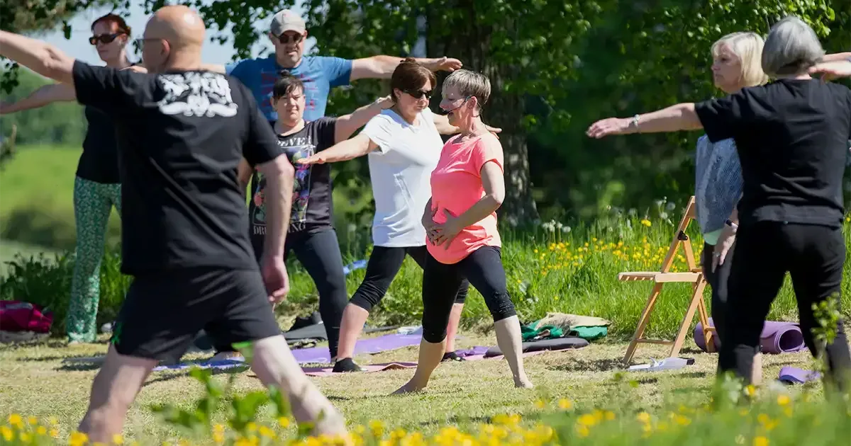 Yoga teacher with hands on her belly instructing students to engage their core muscles when practicing yoga.