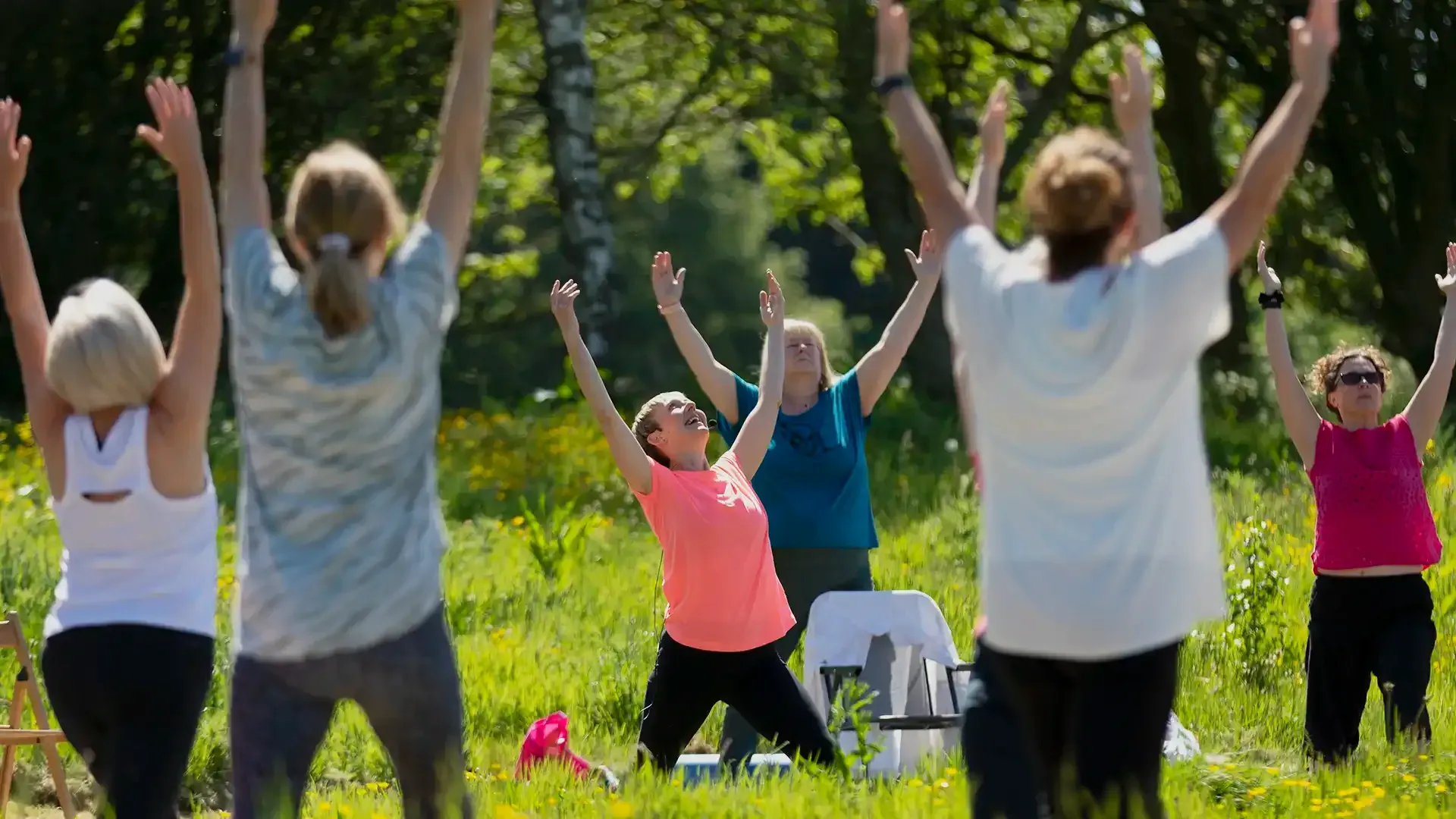 A group of people enjoying a gentle uplifting outdoor yoga session.