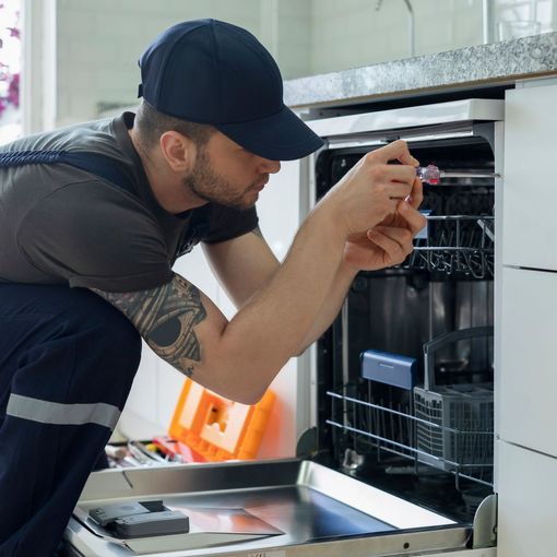 A man is fixing a dishwasher with a screwdriver