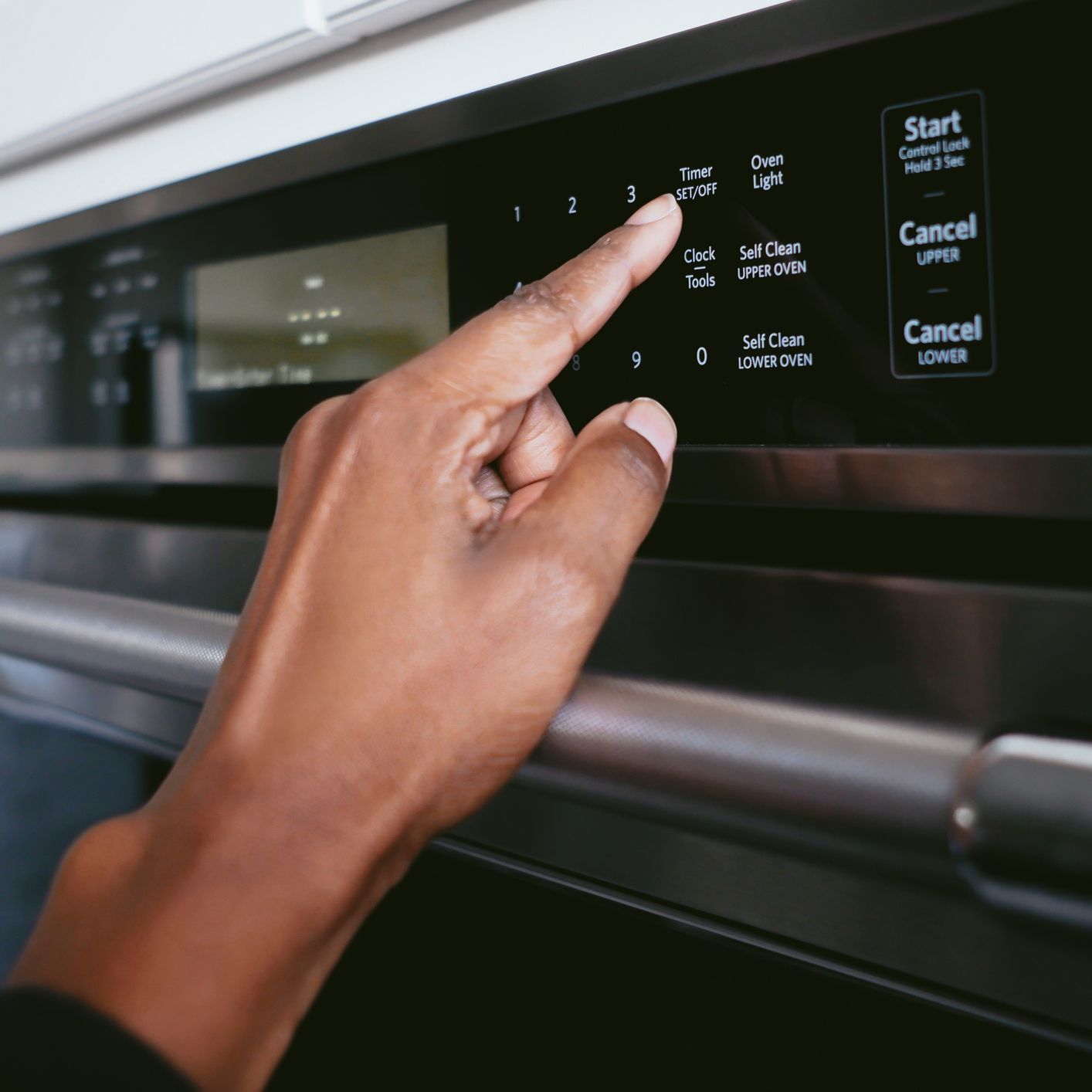 A close up of a person pressing a button on an oven