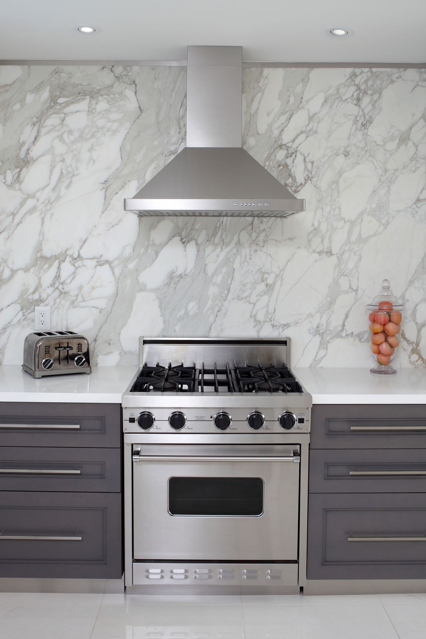 A kitchen with stainless steel appliances and a marble wall