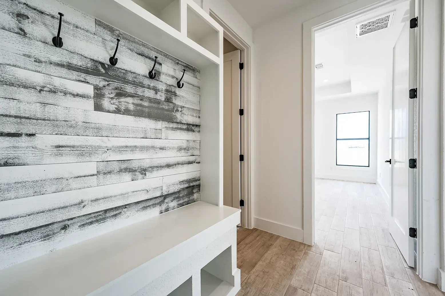 A hallway in a house with a bench and hooks on the wall.