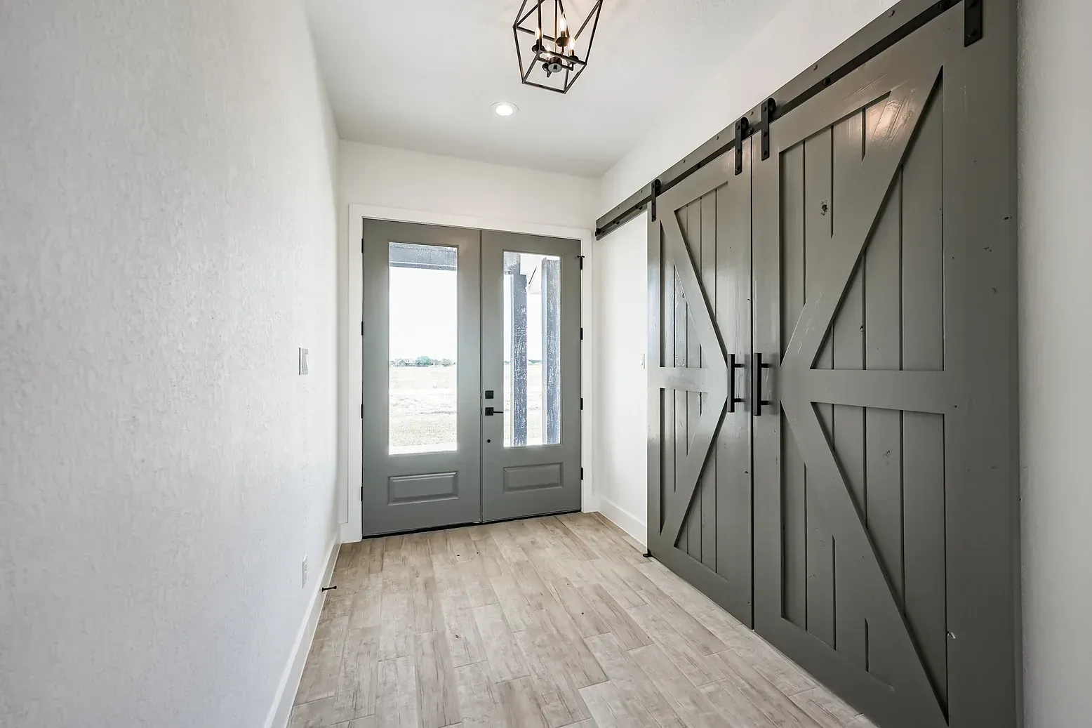 A hallway with sliding barn doors and a chandelier.