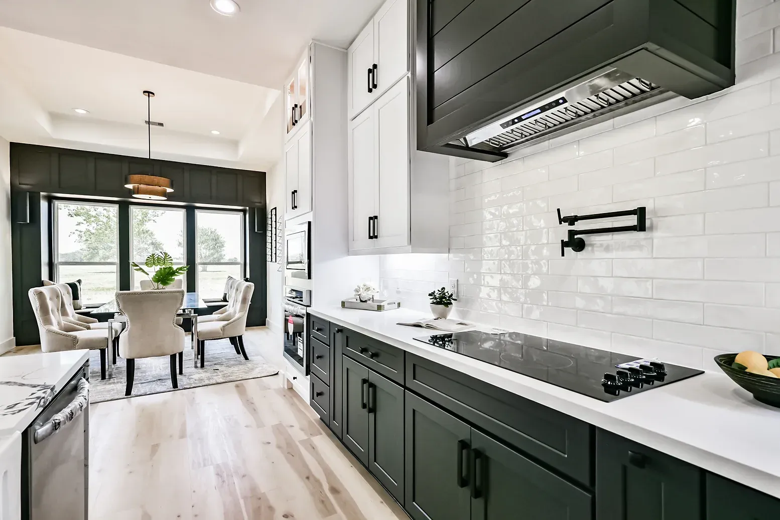 A kitchen with black cabinets and white counter tops and a stove top oven.