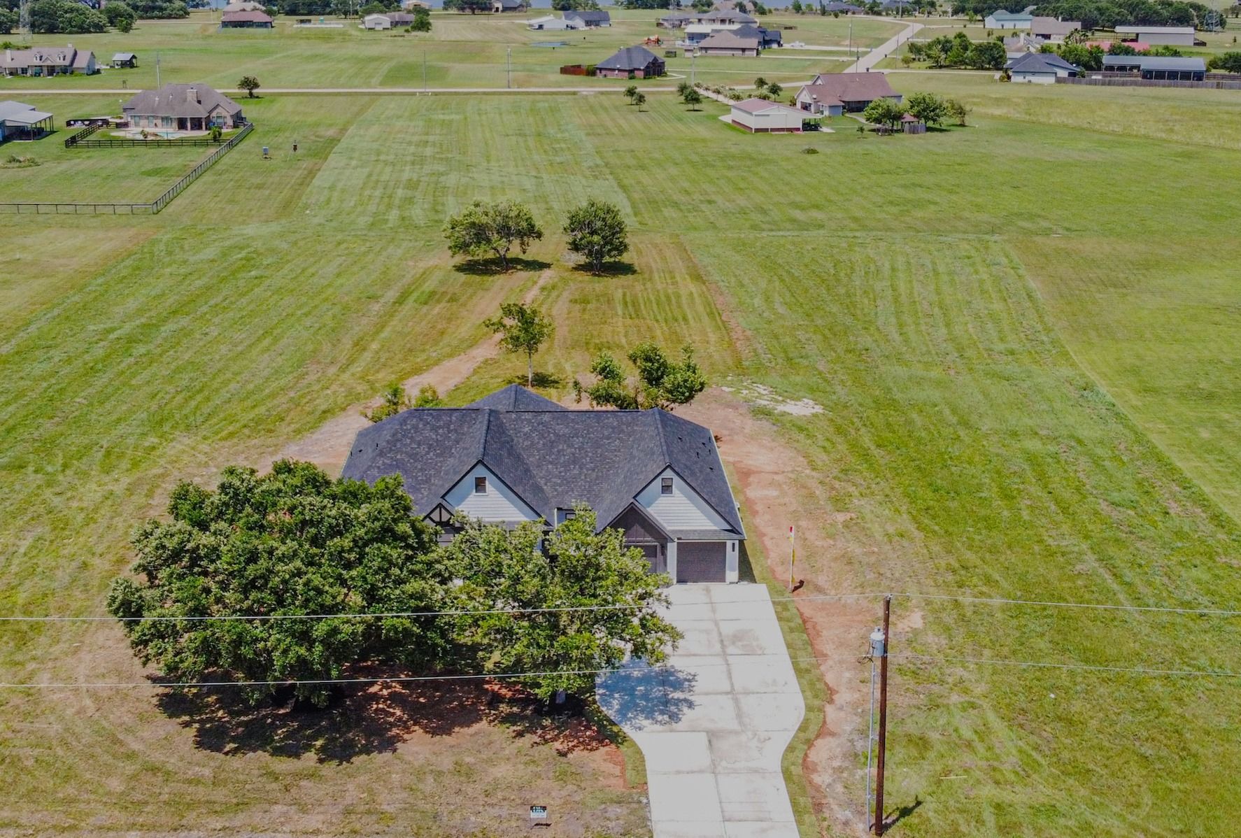 An aerial view of a house in the middle of a grassy field.
