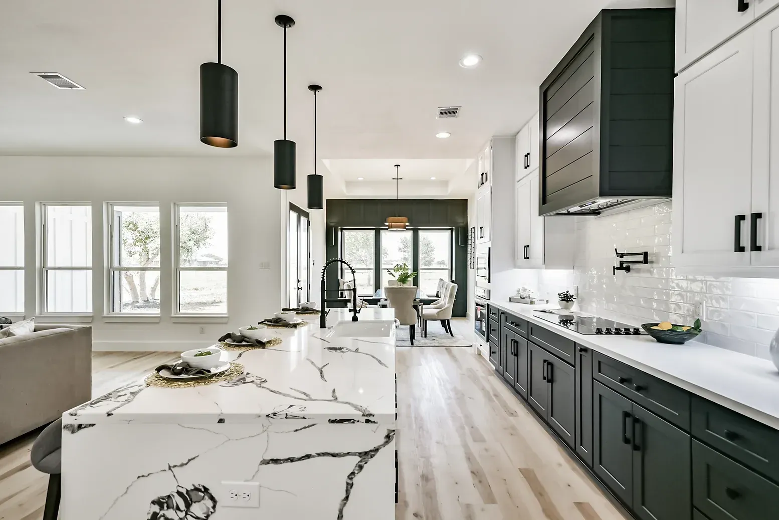 A kitchen with black and white cabinets and a large island in the middle.