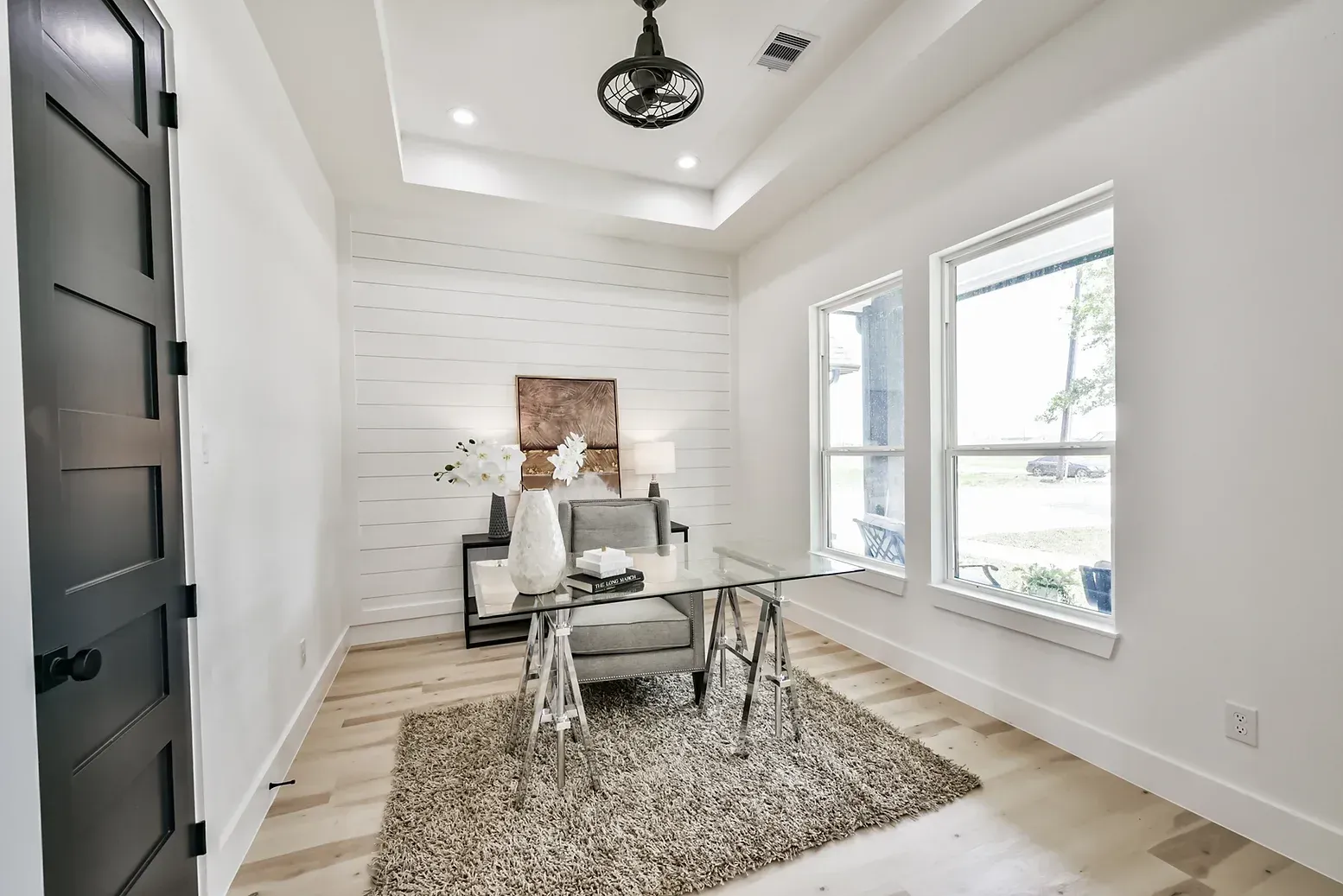 A home office with a desk , chair , rug and ceiling fan.