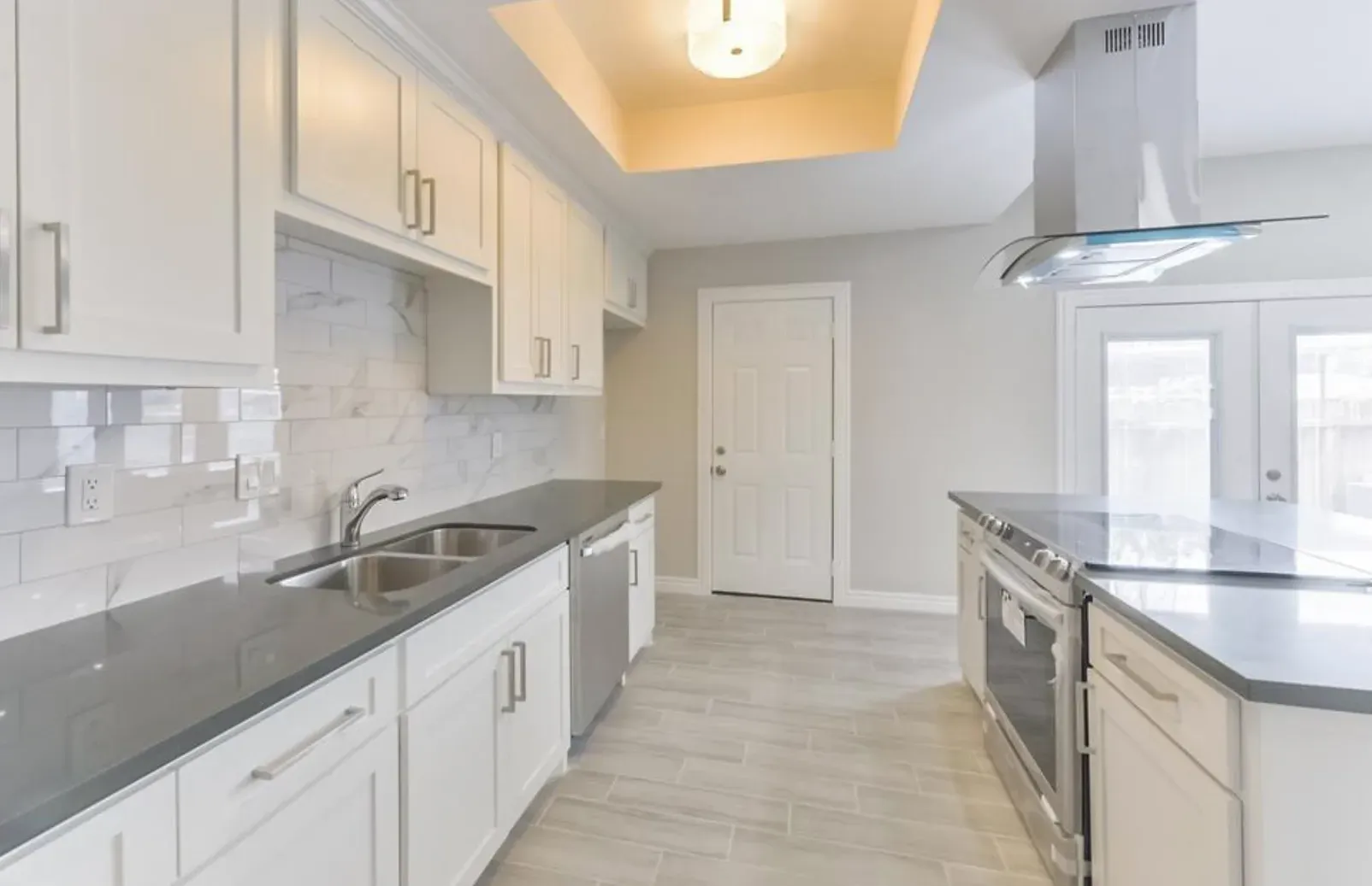 A kitchen with white cabinets and black counter tops