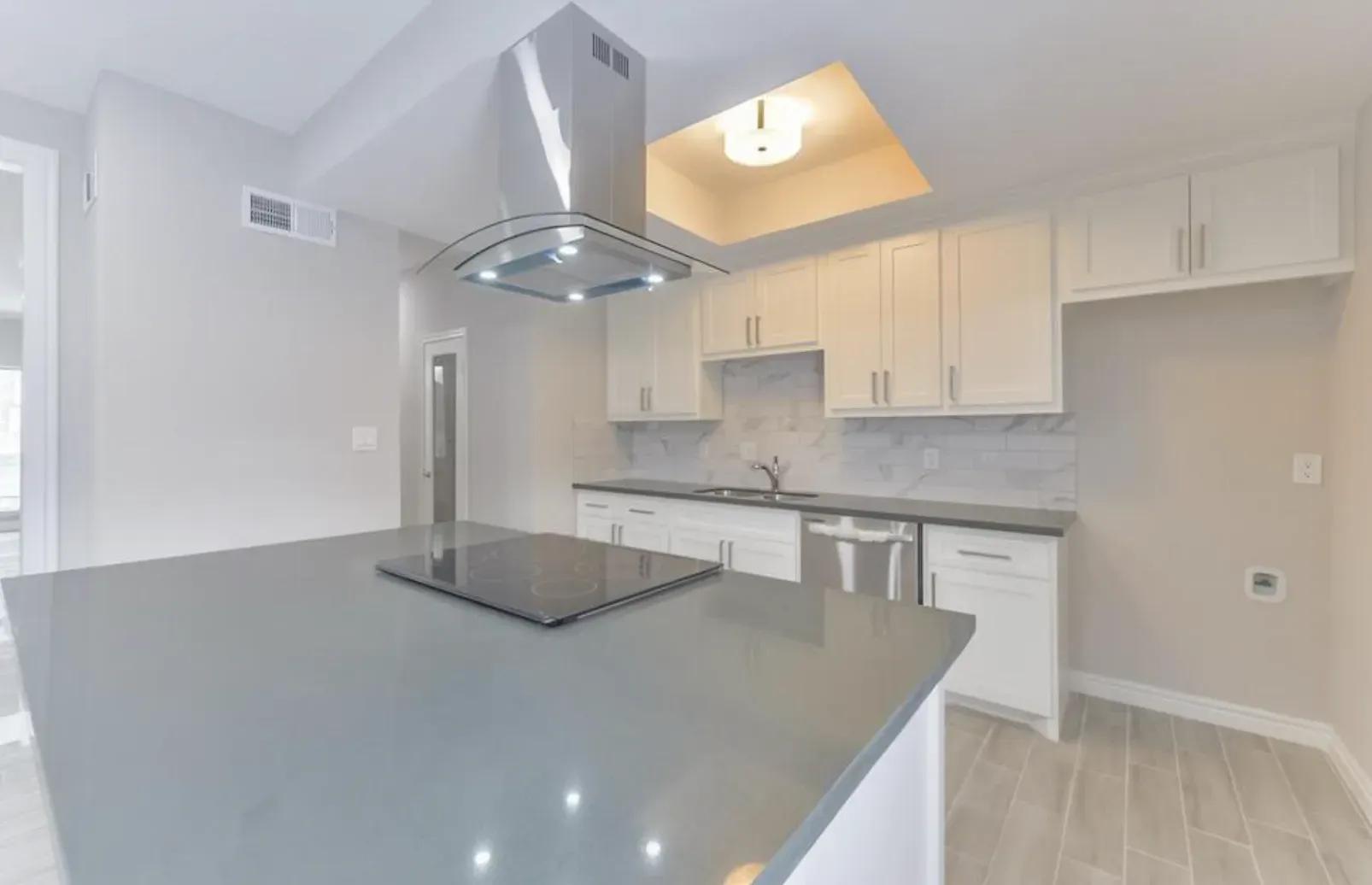 An empty kitchen with white cabinets and a stove top oven.