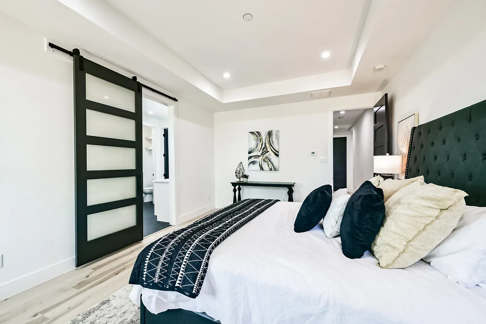 A bedroom with a large bed and a sliding barn door.
