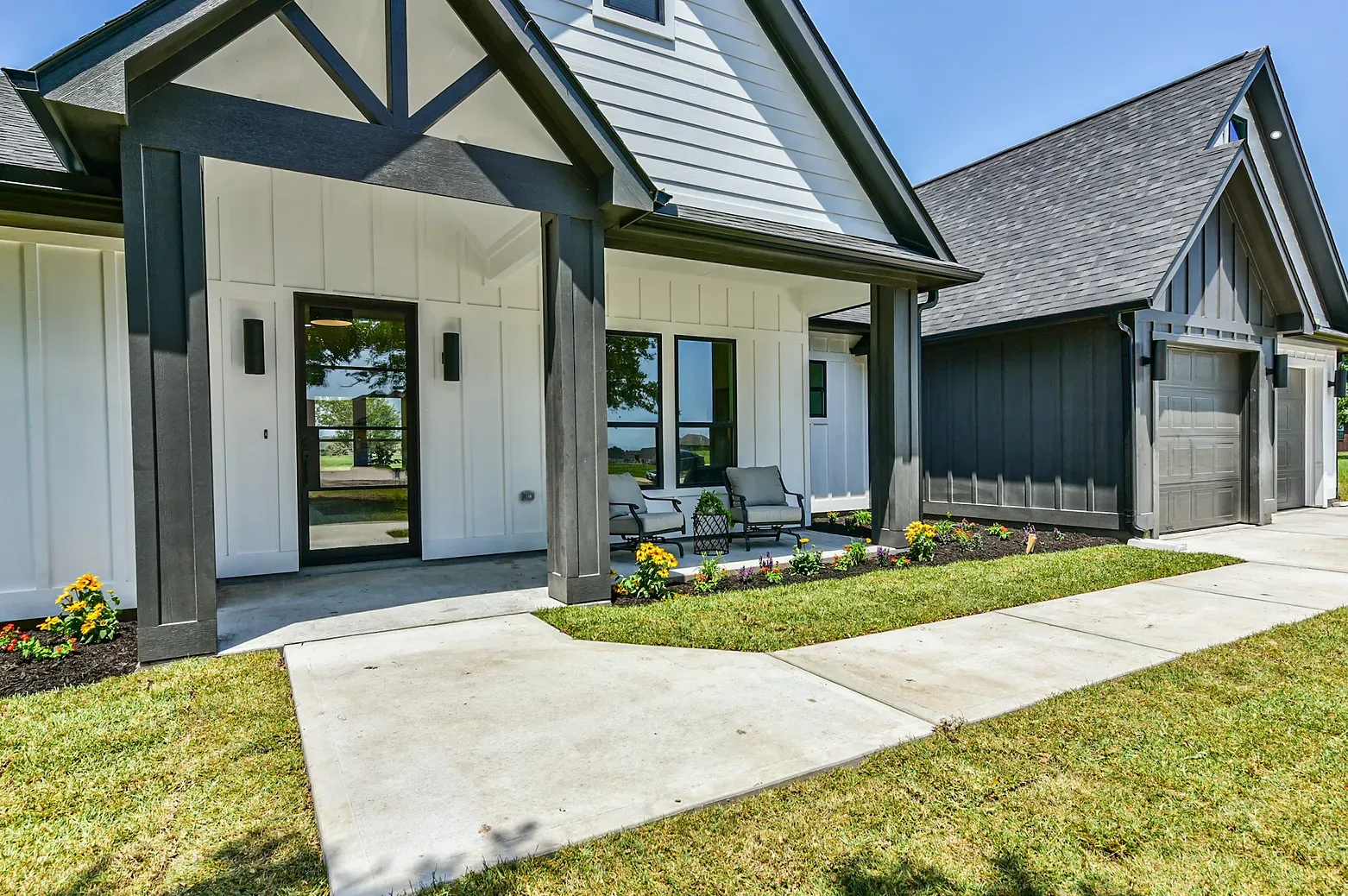 A white and black house with a porch and a garage.
