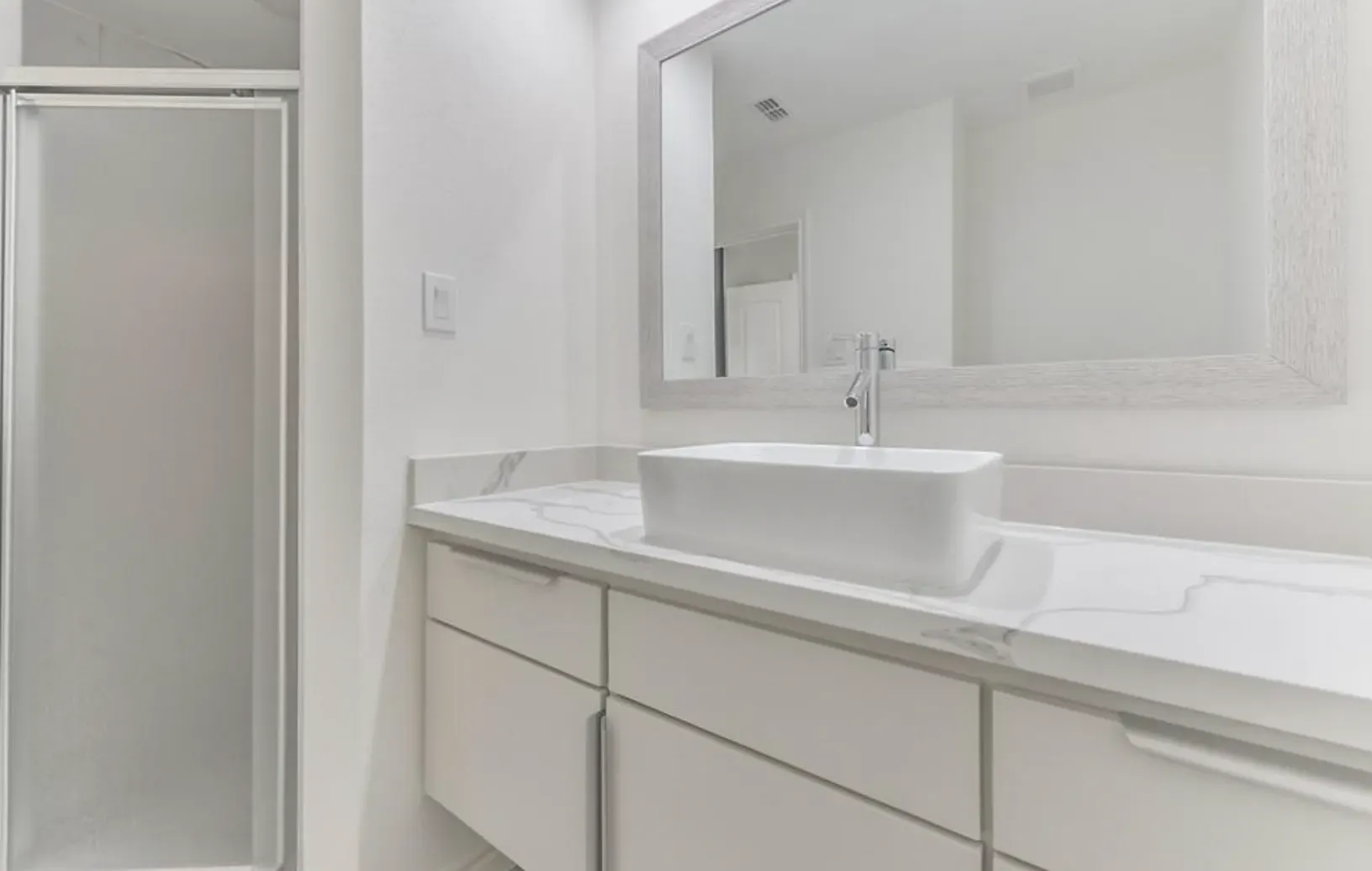 A bathroom with a sink , mirror and shower.