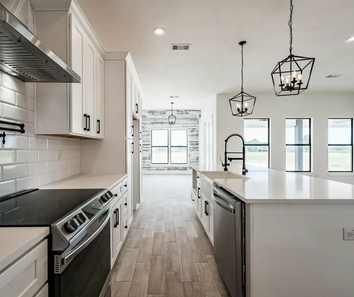 A kitchen with white cabinets , a stove , a sink , and a large island.