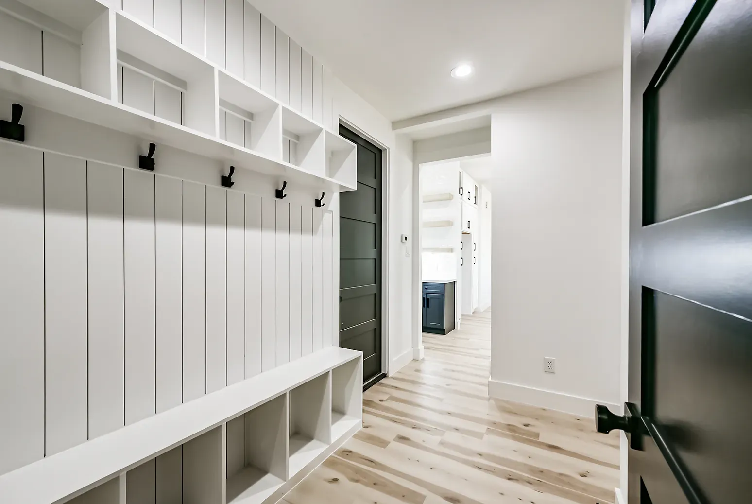 A hallway with a bench and hooks on the wall.