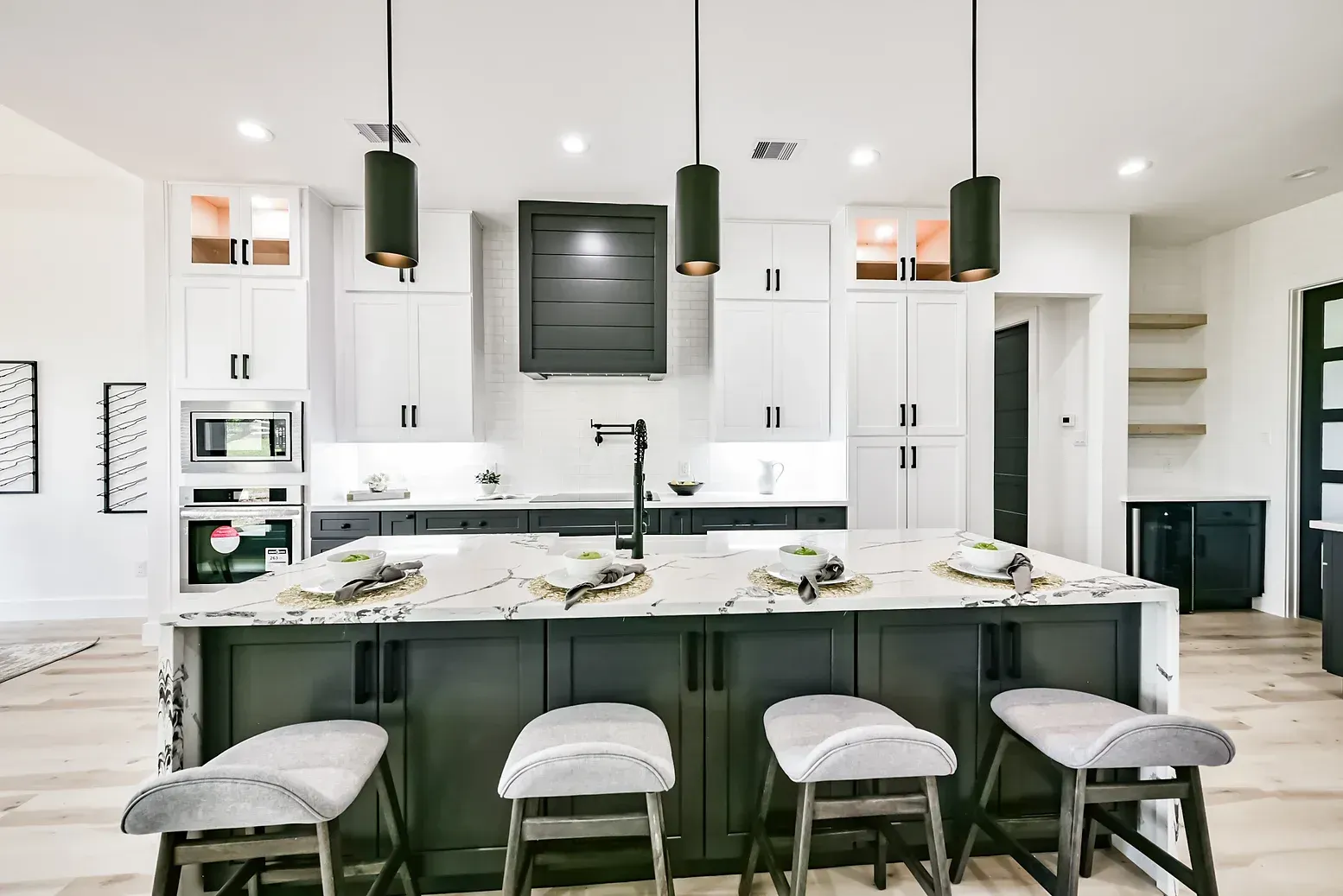 A kitchen with a large island and stools in it.