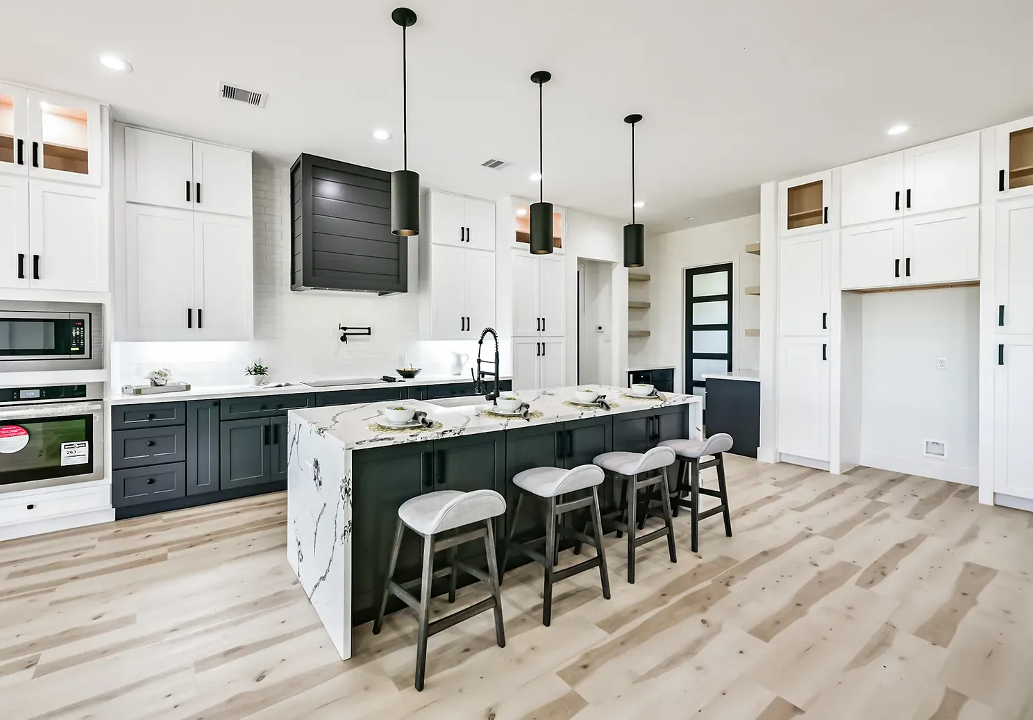 A kitchen with a large island and stools in it.