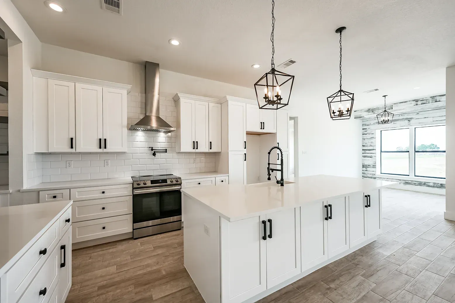 A kitchen with white cabinets , stainless steel appliances , and a large island.