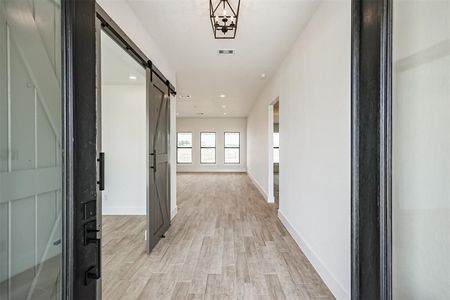A hallway in a house with a sliding barn door.