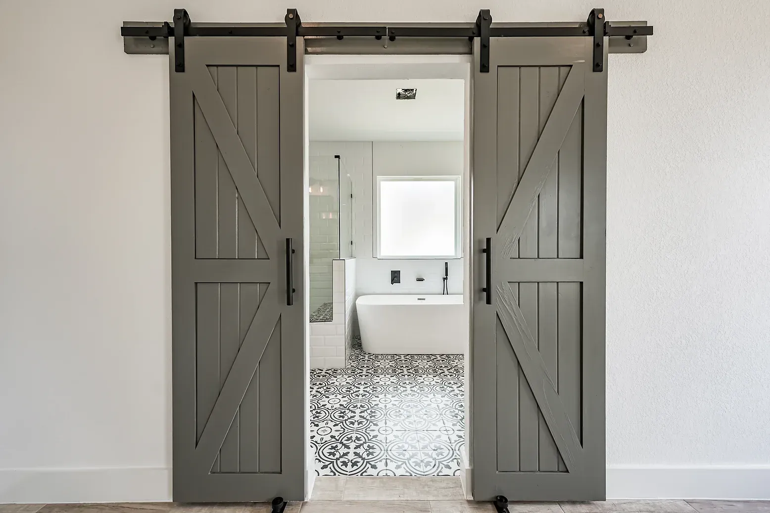 A bathroom with sliding barn doors leading to it.
