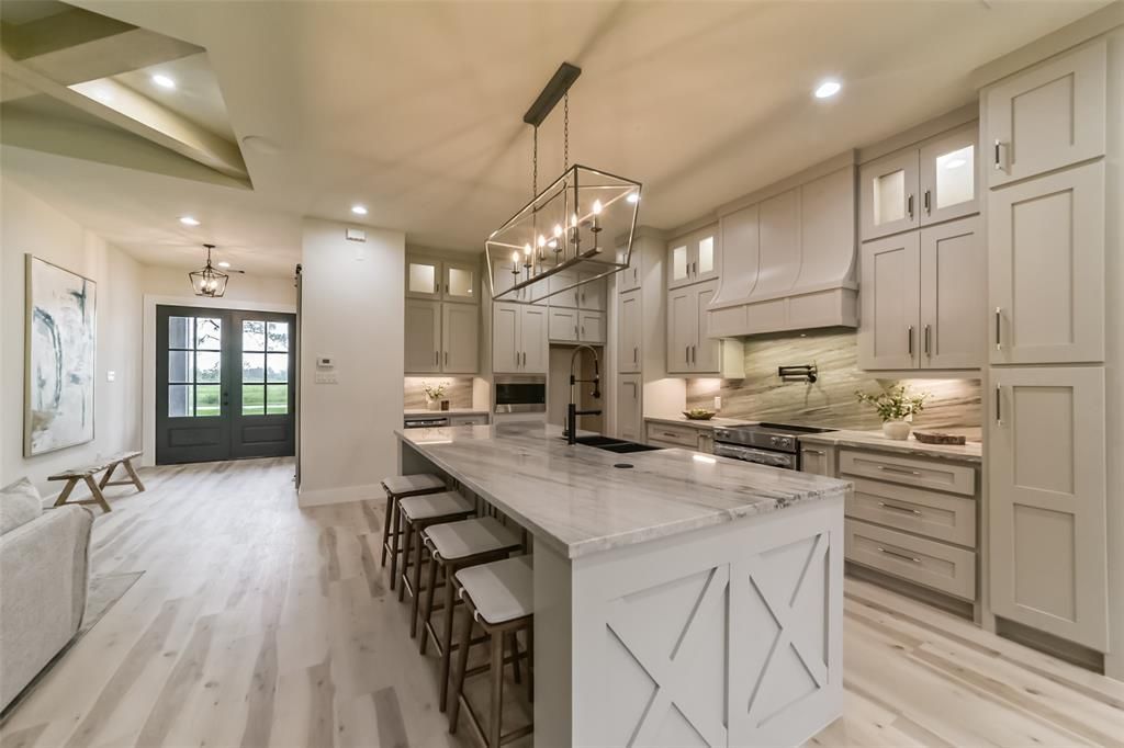 A kitchen with white cabinets and a large island with the letter xxi on it