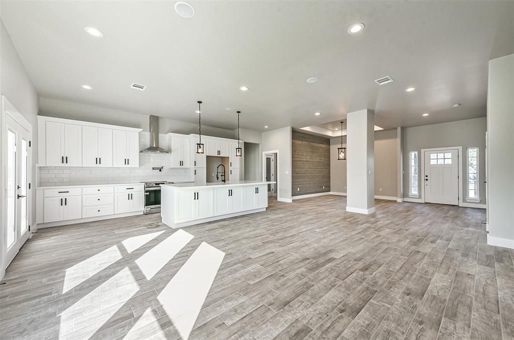 A large empty room with hardwood floors and white cabinets.