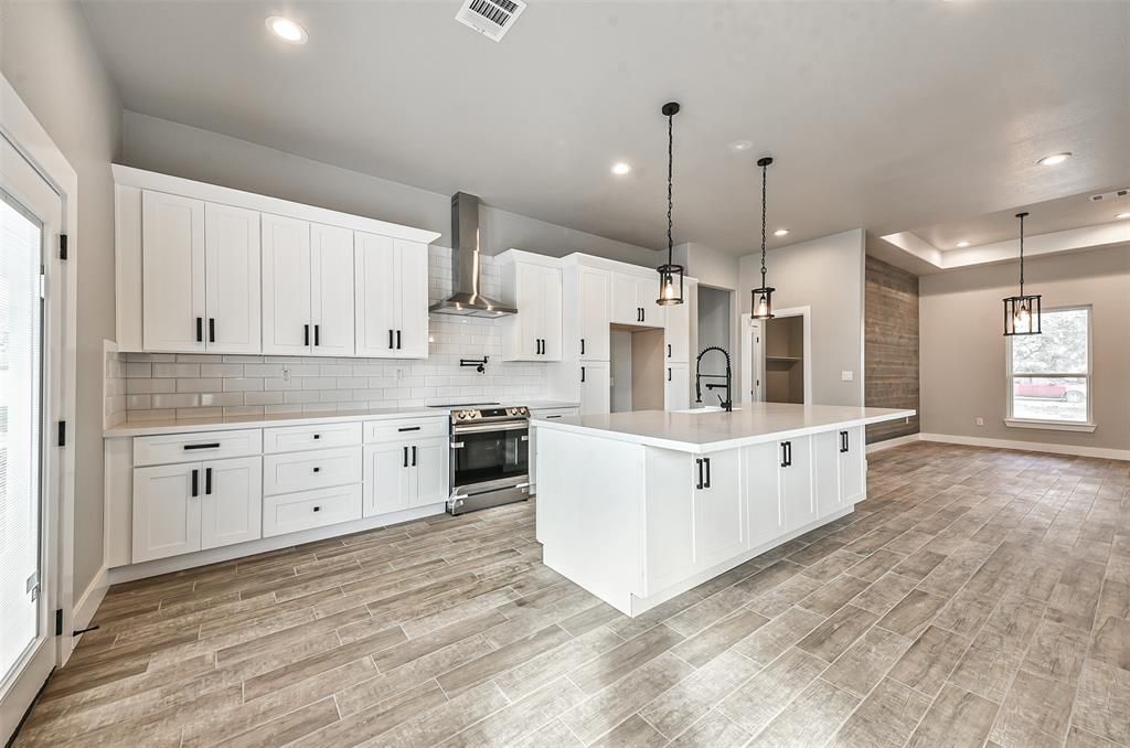 An empty kitchen with white cabinets and a large island.