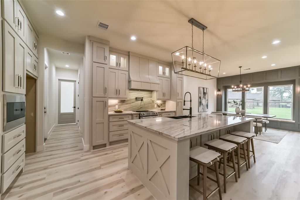 A kitchen with a large island and stools in a house.