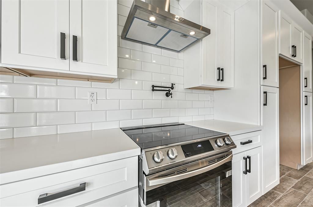 A kitchen with white cabinets and a stove top oven.