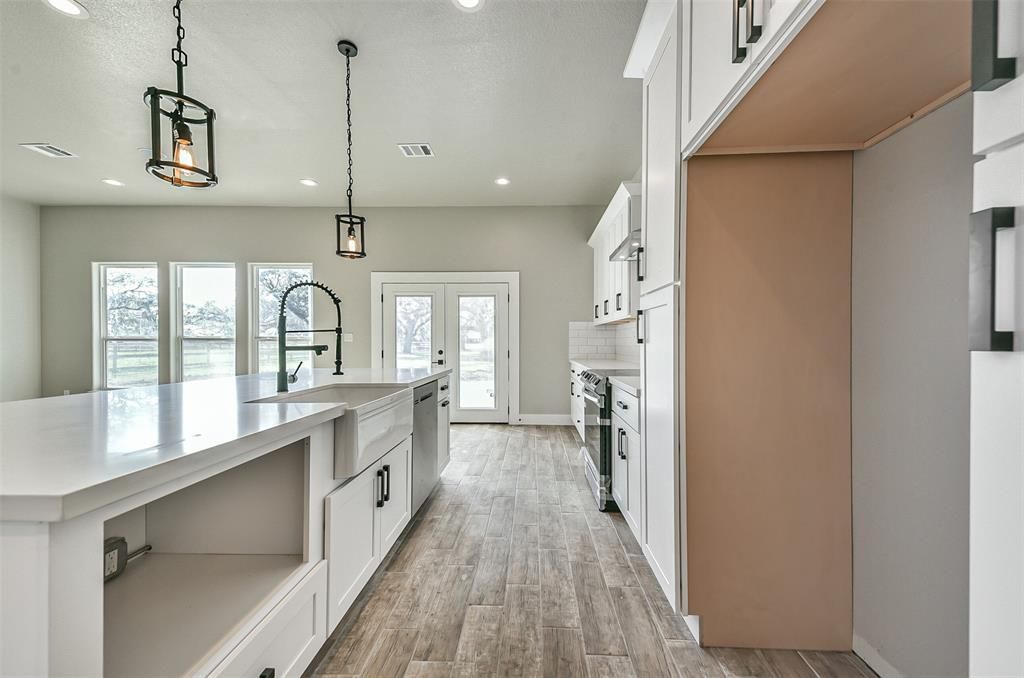 A kitchen with white cabinets and wooden floors