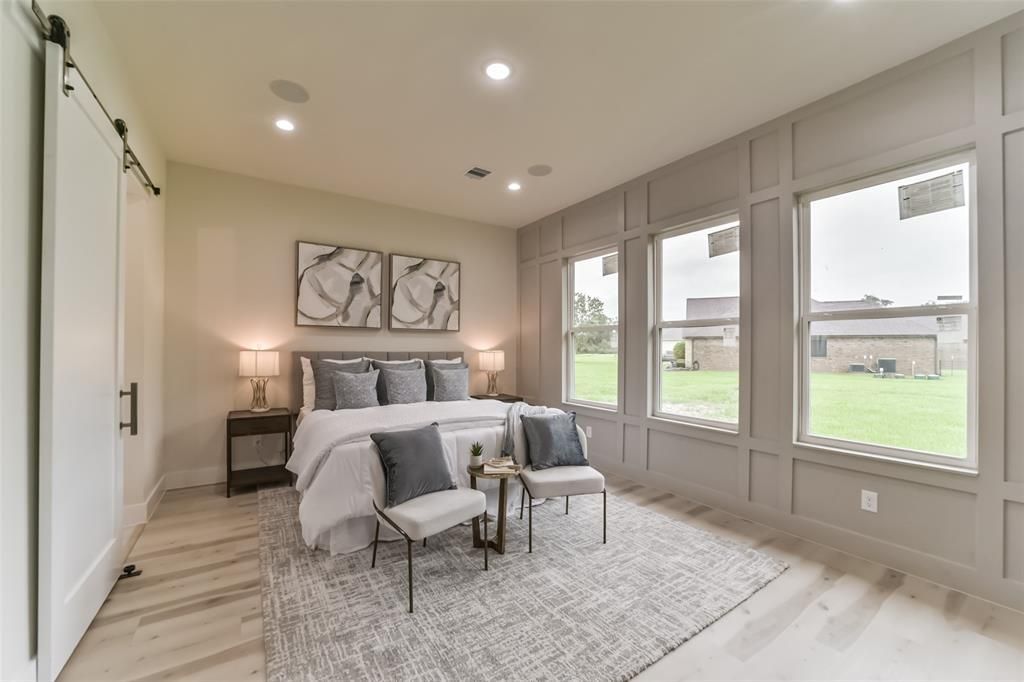 A bedroom with a bed , chairs , and a lot of windows.